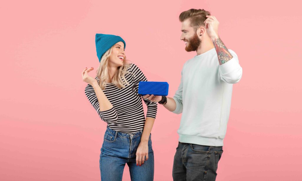 young attractive couple listening to music on wireless speaker